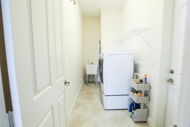 laundry area featuring light tile patterned floors, laundry area, baseboards, and a sink