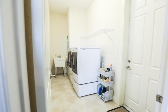 washroom featuring laundry area, light tile patterned floors, separate washer and dryer, and a sink