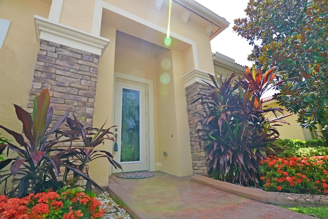 doorway to property with stone siding and stucco siding