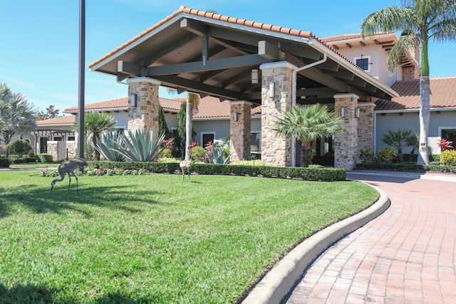 view of front of home featuring stucco siding, stone siding, a front yard, and a tile roof