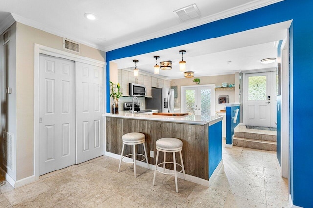 kitchen featuring sink, stainless steel refrigerator with ice dispenser, kitchen peninsula, crown molding, and a breakfast bar area