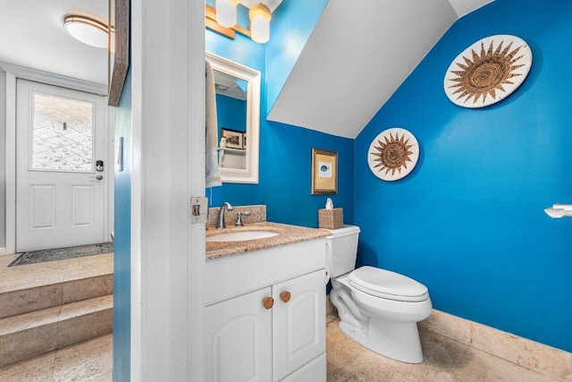 bathroom featuring toilet, vanity, and vaulted ceiling