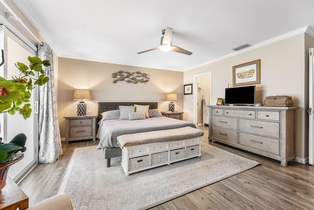 bedroom featuring ceiling fan, light wood-type flooring, and crown molding