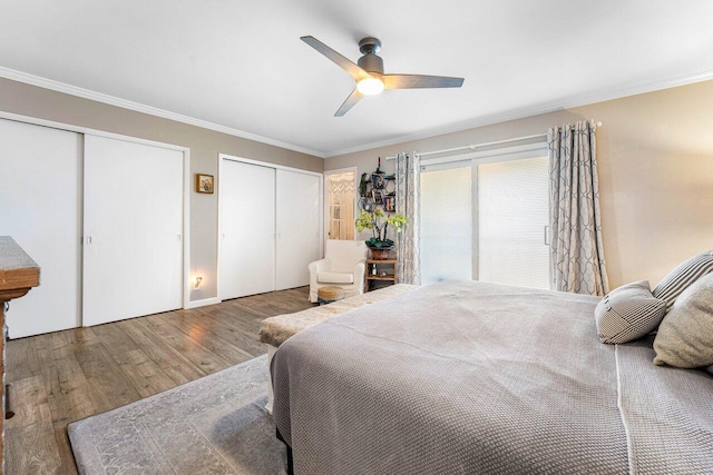 bedroom featuring hardwood / wood-style floors, ceiling fan, crown molding, and multiple closets