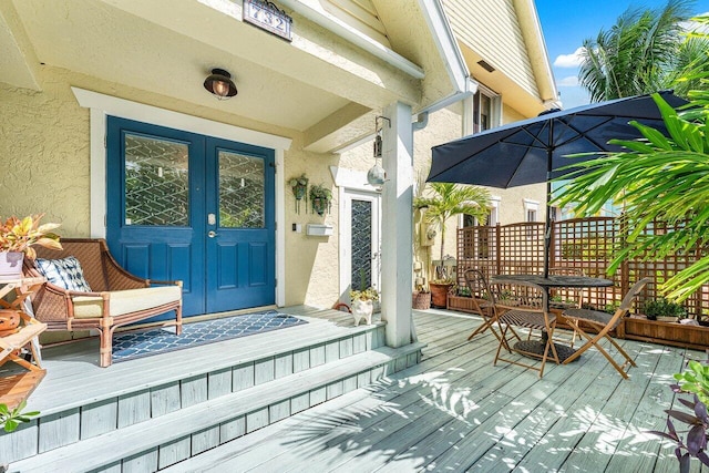 view of exterior entry featuring a wooden deck and french doors