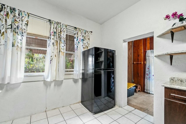 kitchen with black refrigerator and light tile patterned flooring