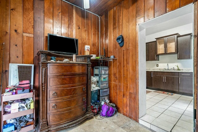 misc room with wood walls, sink, and light tile patterned floors