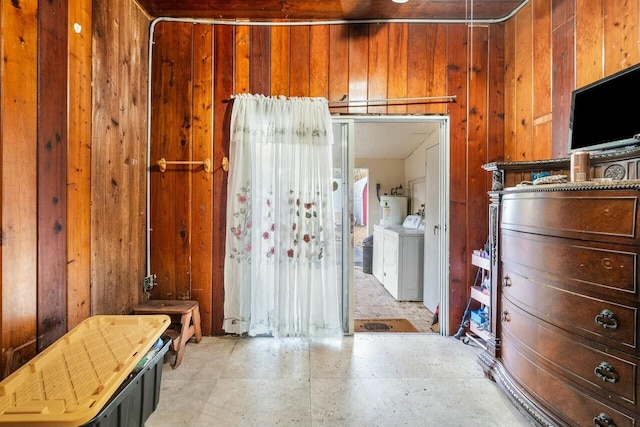 interior space featuring washer and dryer, water heater, and wood walls