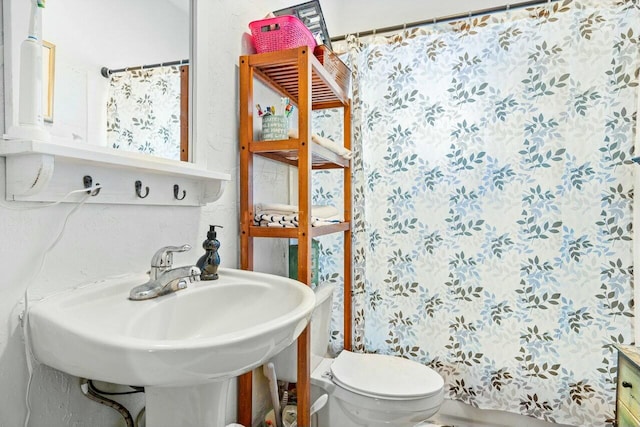 bathroom featuring walk in shower, sink, and toilet