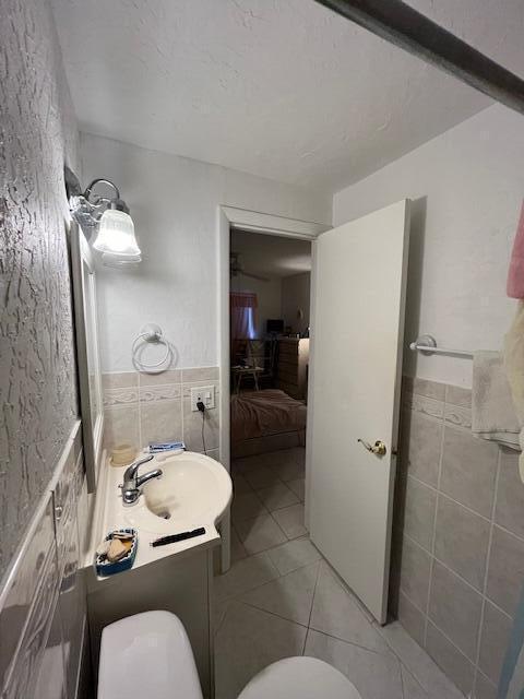 bathroom featuring tile patterned floors, vanity, toilet, and tile walls