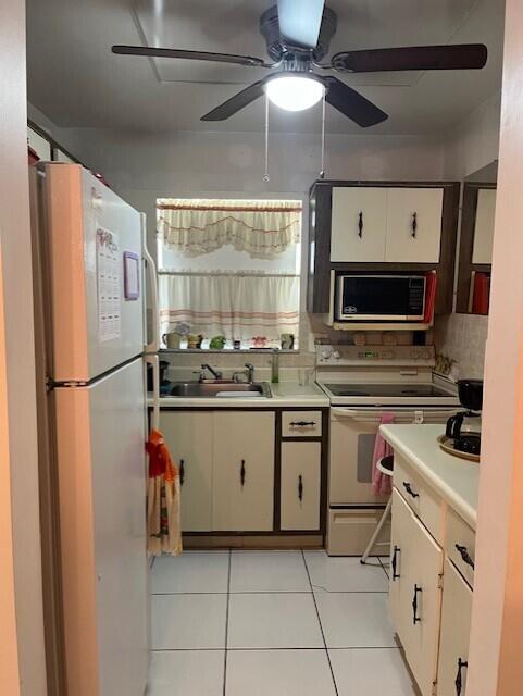 kitchen featuring white appliances, white cabinets, sink, ceiling fan, and light tile patterned floors