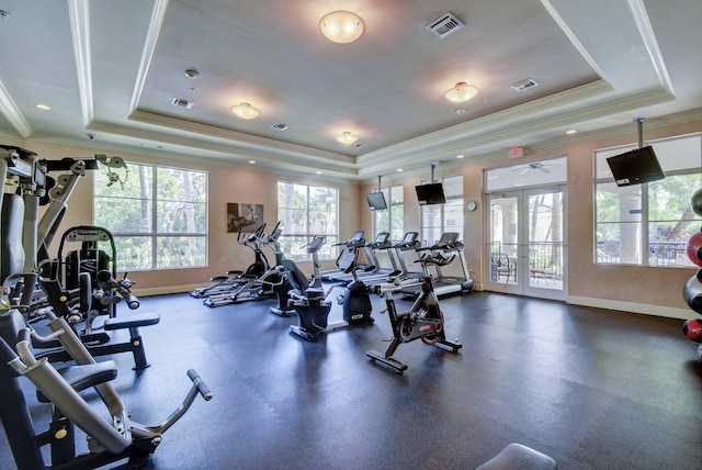 gym featuring a raised ceiling, crown molding, a wealth of natural light, and french doors