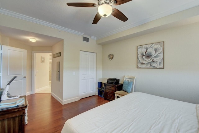 bedroom with dark wood-type flooring, ceiling fan, a closet, and crown molding