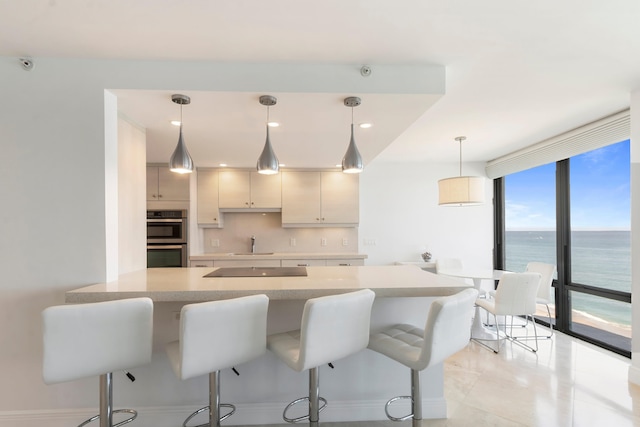 kitchen with backsplash, floor to ceiling windows, a water view, and decorative light fixtures