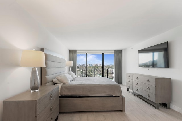 bedroom with floor to ceiling windows and light wood-type flooring