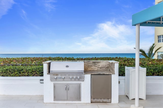 view of patio / terrace featuring an outdoor kitchen, a water view, and area for grilling