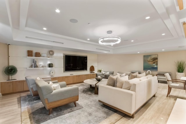 living room with light hardwood / wood-style floors and a raised ceiling