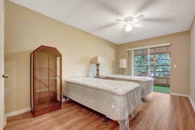 bedroom with ceiling fan, light wood-type flooring, and a textured ceiling