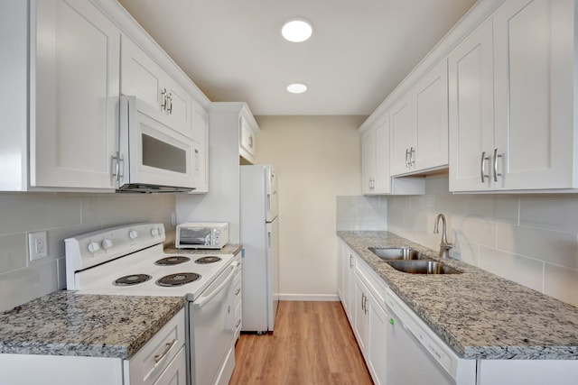 kitchen with white appliances, sink, light hardwood / wood-style floors, light stone counters, and white cabinetry