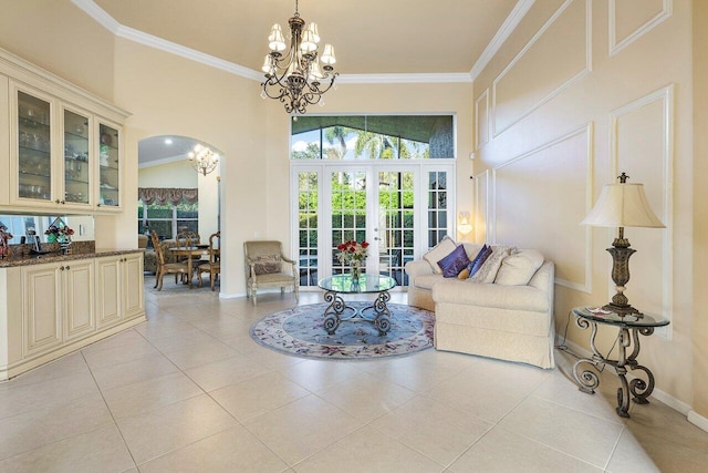 living room with french doors, crown molding, an inviting chandelier, and light tile patterned floors