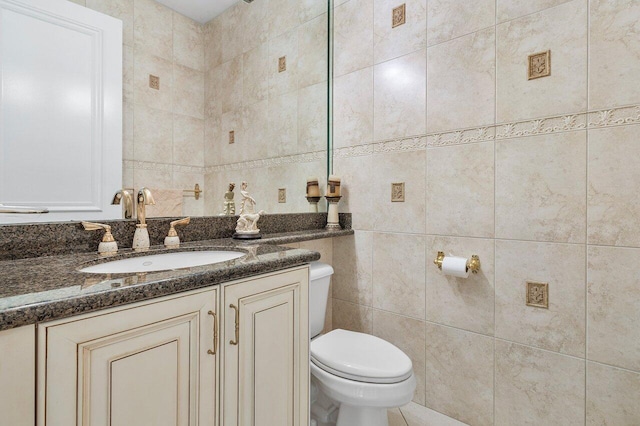 bathroom with vanity, toilet, and tile walls