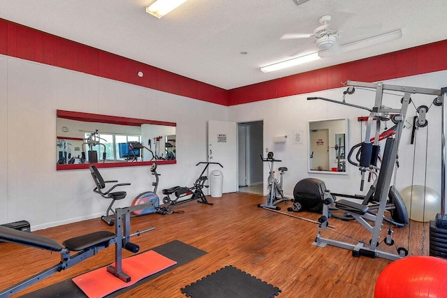 gym with ceiling fan, a textured ceiling, and hardwood / wood-style flooring