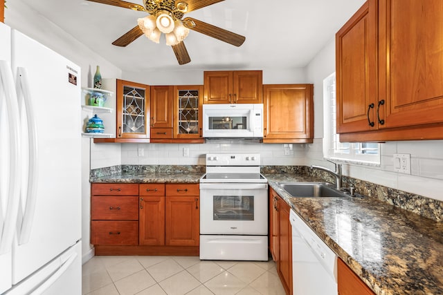 kitchen with sink, dark stone countertops, backsplash, light tile patterned floors, and white appliances