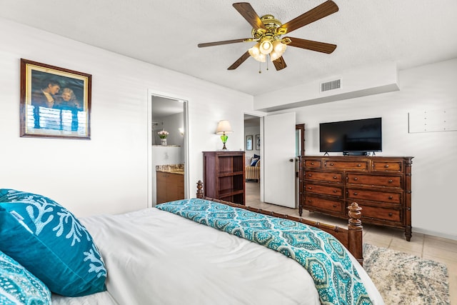 tiled bedroom featuring ceiling fan, a textured ceiling, and ensuite bath