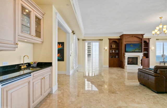 kitchen featuring pendant lighting, dark stone counters, sink, crown molding, and a large fireplace