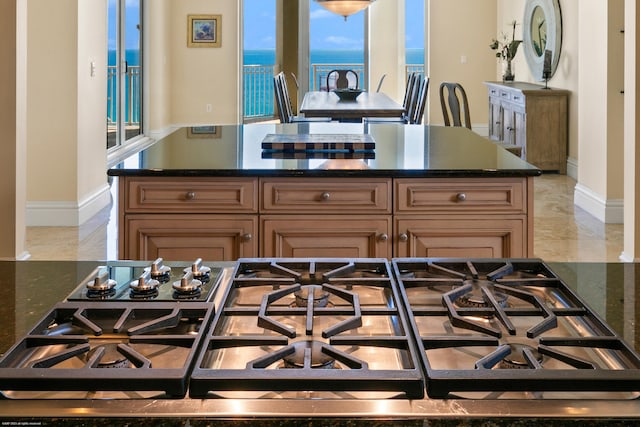 kitchen with gas cooktop, a water view, and dark stone counters