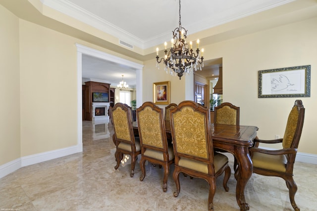 dining room with ornate columns, a fireplace, a chandelier, and ornamental molding