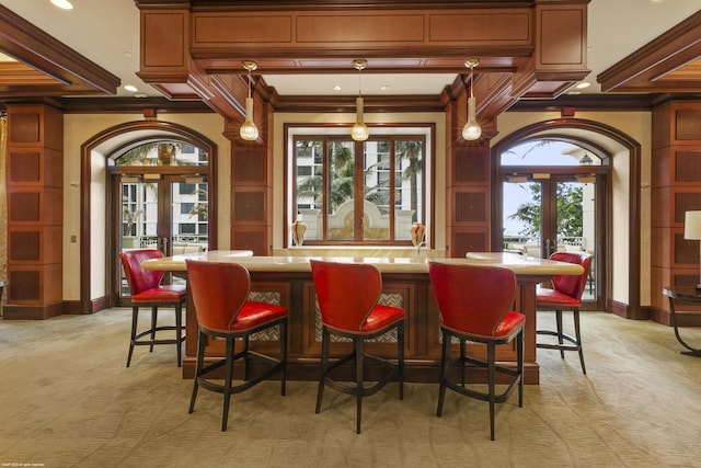 bar with light carpet, french doors, hanging light fixtures, and crown molding