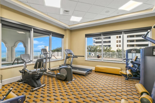 exercise area with carpet, a drop ceiling, and a water view