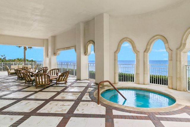 view of pool with a water view, a hot tub, and a patio area