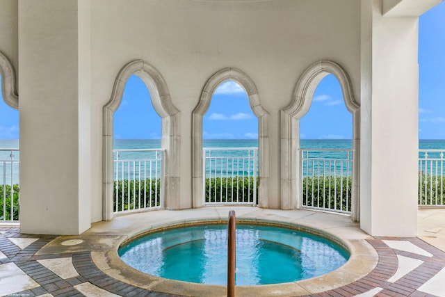 view of pool with a water view and an in ground hot tub