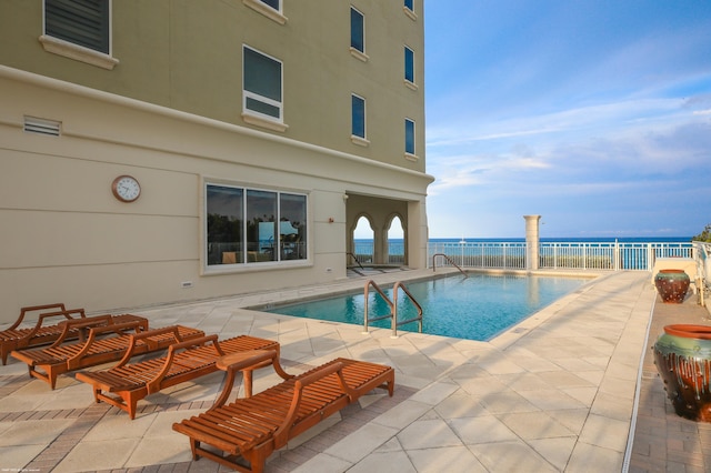 view of pool with a water view and a patio