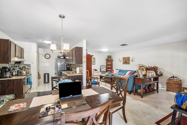 dining room with sink, light tile patterned floors, and an inviting chandelier