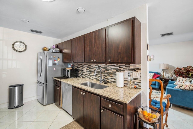 kitchen featuring light stone countertops, sink, stainless steel appliances, dark brown cabinets, and light tile patterned floors