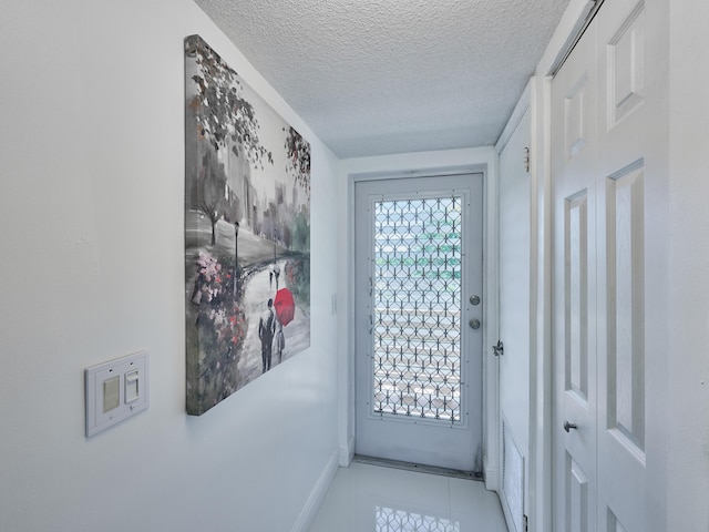 entryway with light tile patterned floors and a textured ceiling