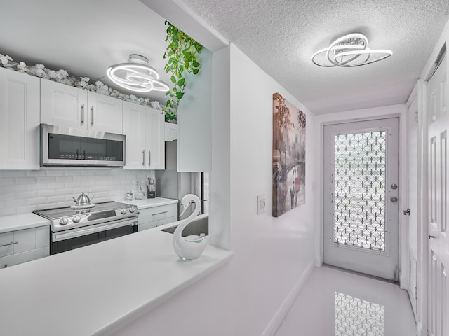 kitchen featuring backsplash, sink, light tile patterned floors, white cabinetry, and stainless steel appliances