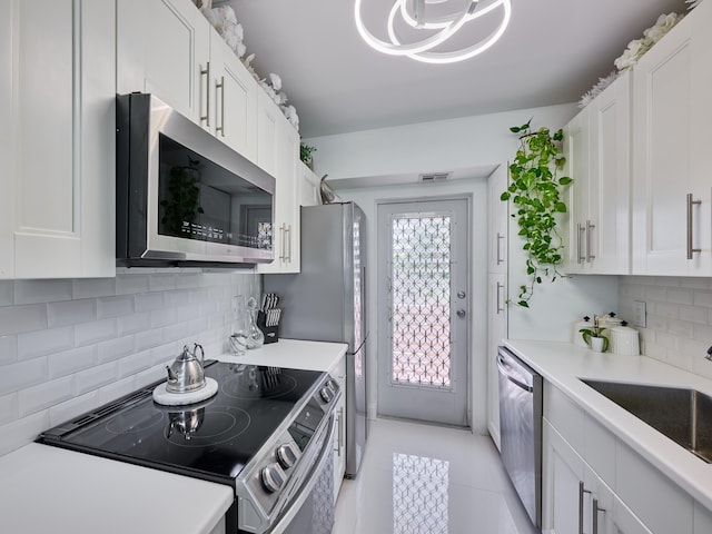 kitchen with white cabinets, sink, decorative backsplash, light tile patterned floors, and stainless steel appliances