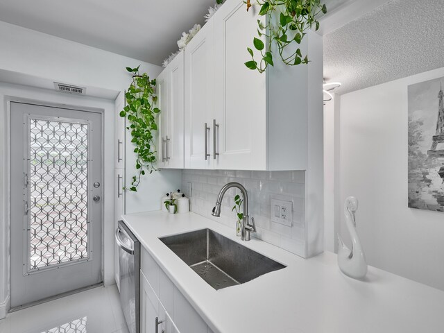 kitchen featuring dishwasher, sink, backsplash, a textured ceiling, and white cabinets