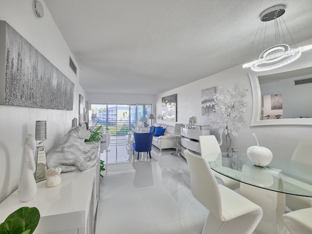 dining area featuring a chandelier, a textured ceiling, and tile patterned flooring