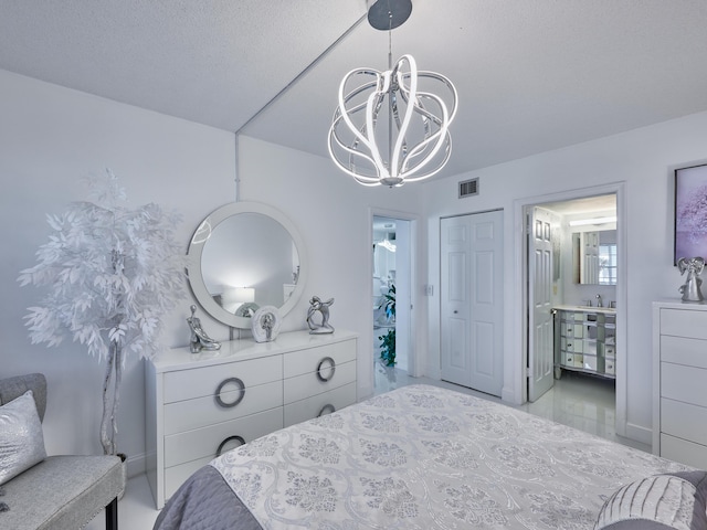 bedroom featuring ensuite bath, sink, a notable chandelier, a textured ceiling, and a closet