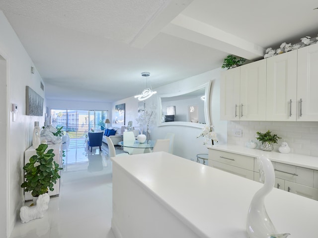 kitchen featuring white cabinets, decorative light fixtures, beam ceiling, and tasteful backsplash