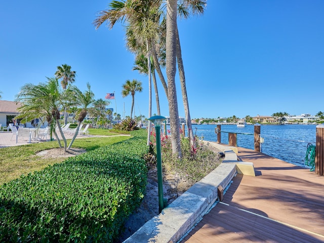 view of dock with a lawn and a water view