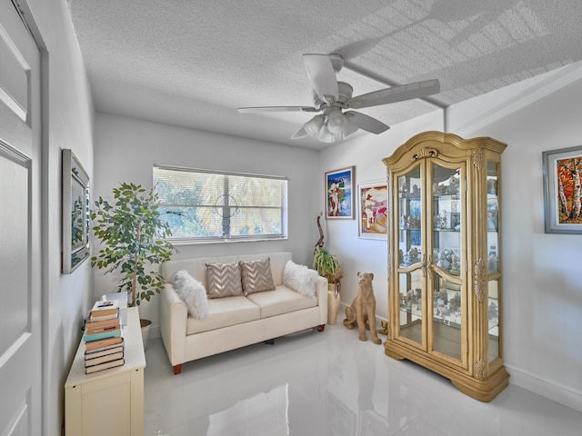 living area with ceiling fan and a textured ceiling