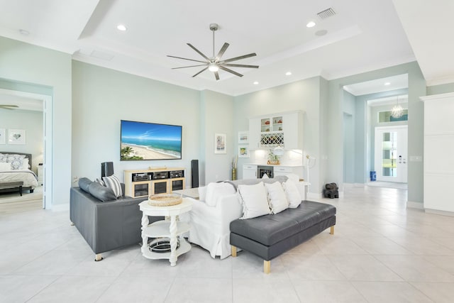 tiled living room featuring a raised ceiling, ceiling fan, and crown molding