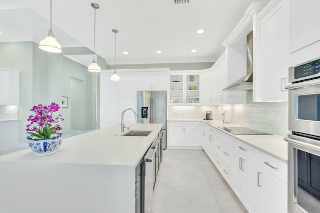 kitchen with wall chimney exhaust hood, double oven, black electric cooktop, a center island with sink, and white cabinets