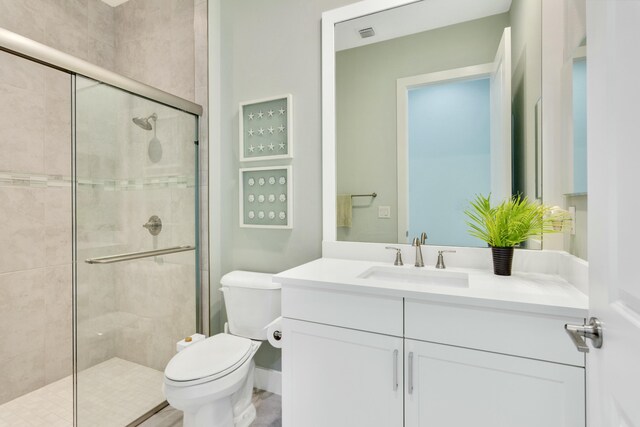 bathroom with vanity, toilet, and a shower with door